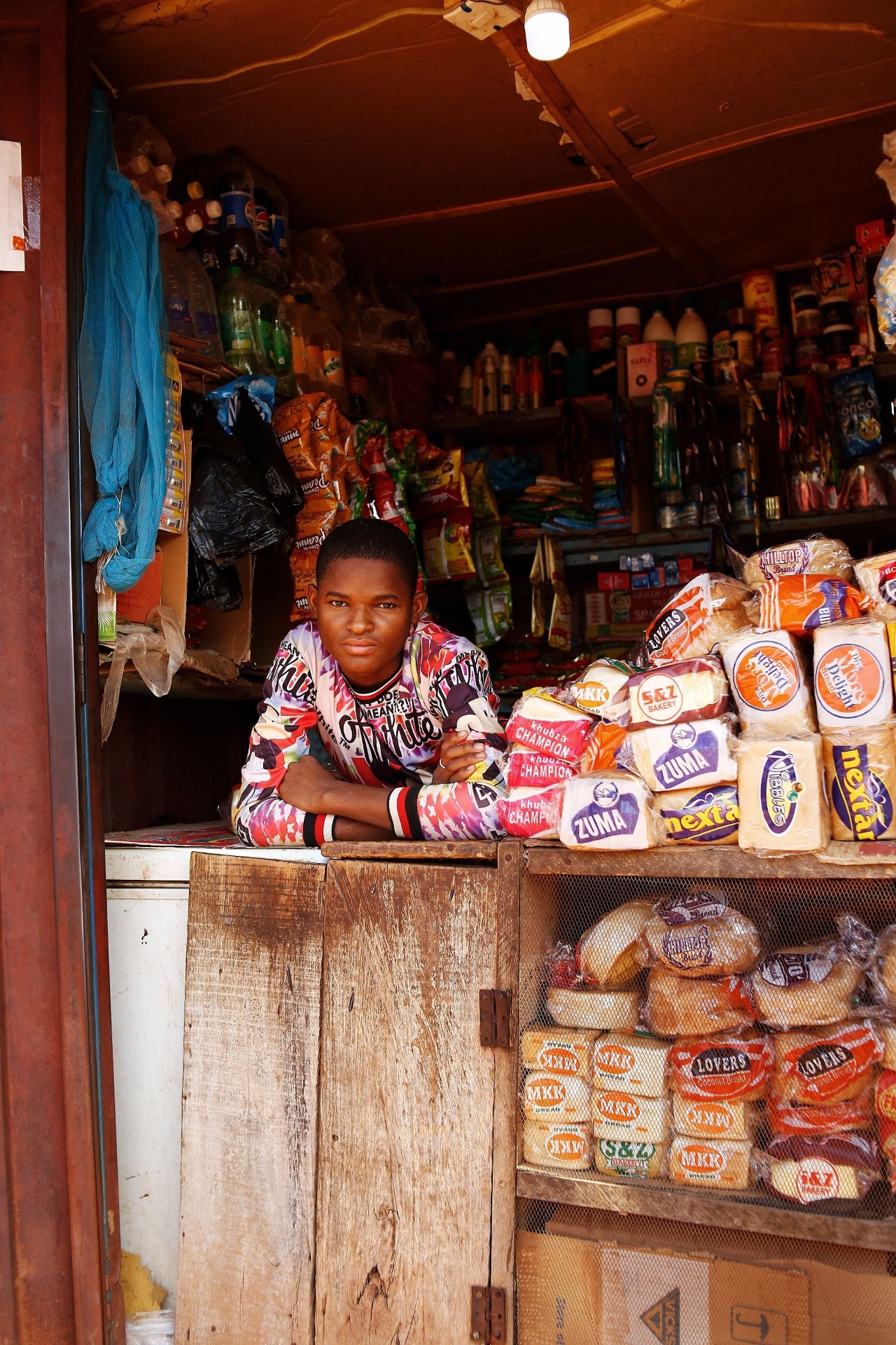 Young shopkeeper at the counter of a well-stocked spaza shop