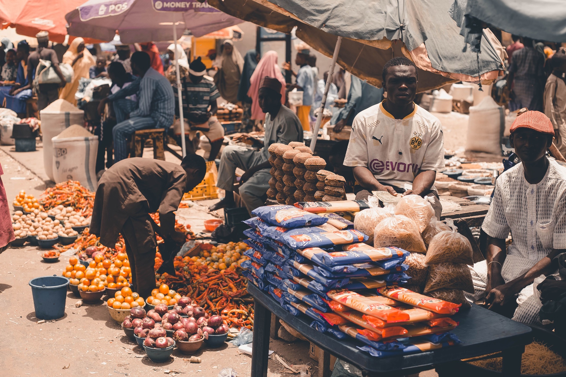 Vendor selling groceries and staples at an open-air market